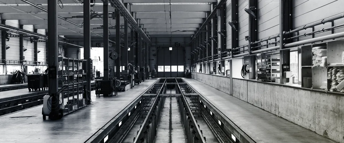 Photograph of an industrial assembly line, treated in the Vandeni navy-and-gold palette.